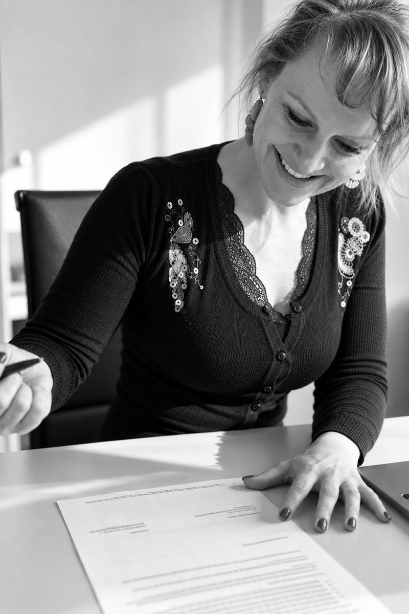Bettina Kochheim sitzt am Schreibtisch und arbeitet mit dem Stift in der Hand an einem ausgedruckten Dokument.